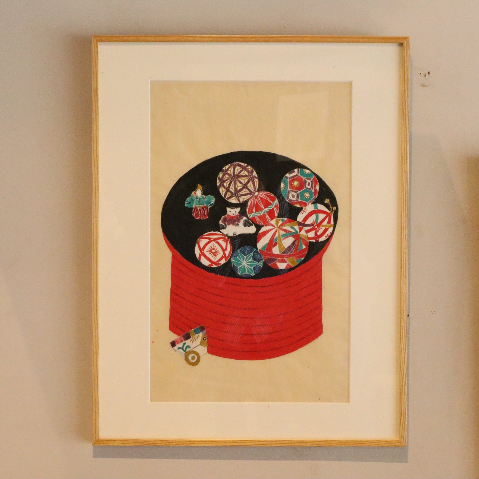赤い器に盛られた色とりどりの手毬を描いた額装の作品