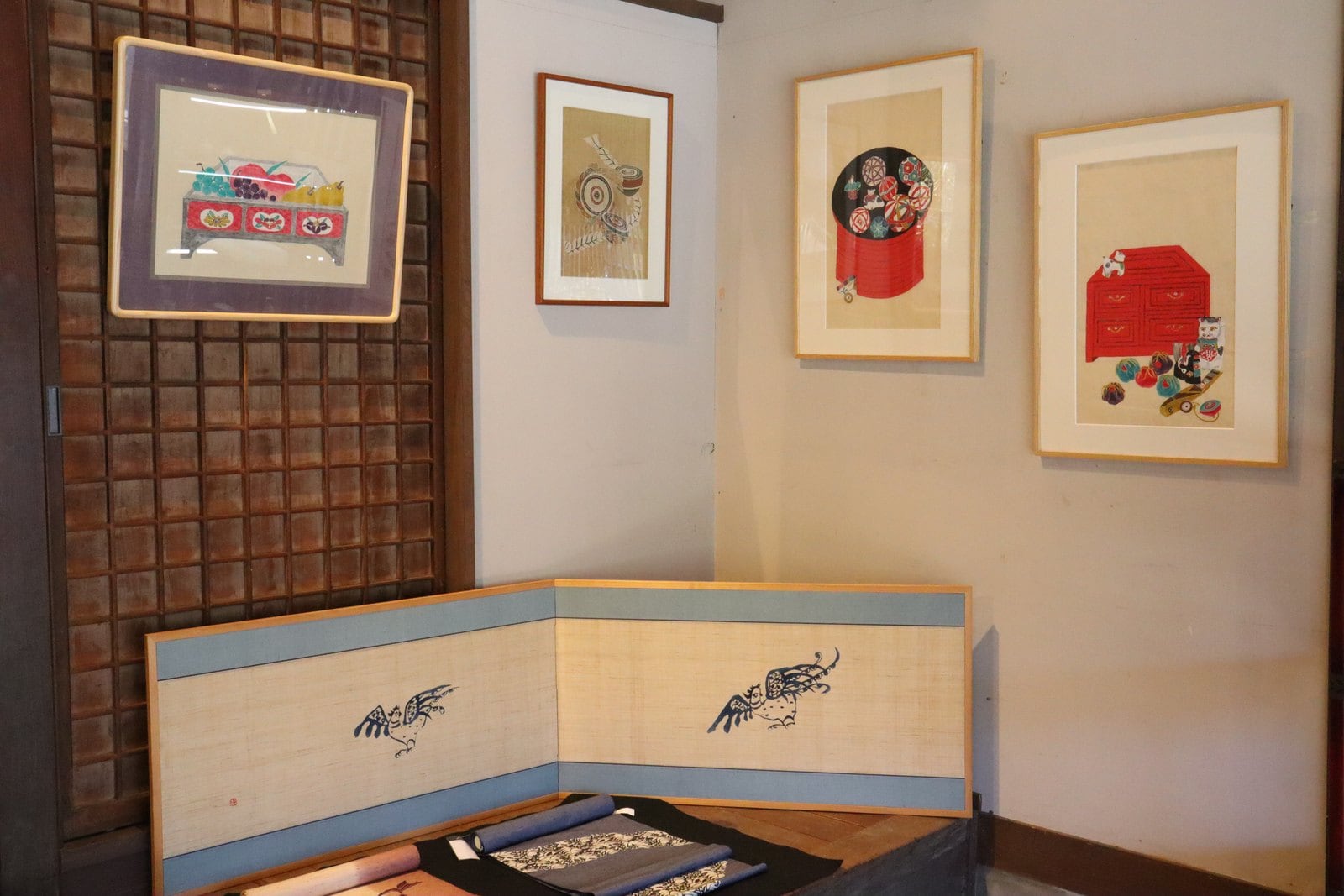 和室の壁に額装の作品が並び、手前に屏風が置かれている展示風景
