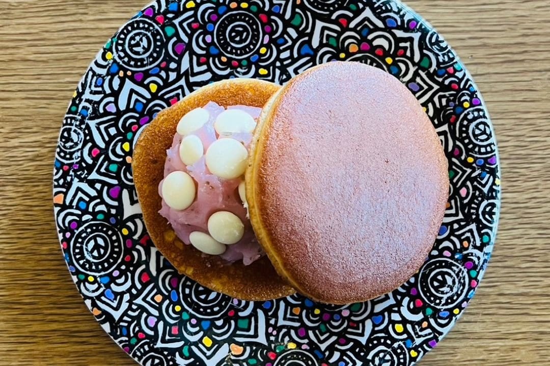 A dorayaki filled with pink cream on a patterned plate